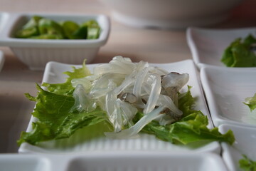 Sliced squid on lettuce leaf in white plate on wooden table