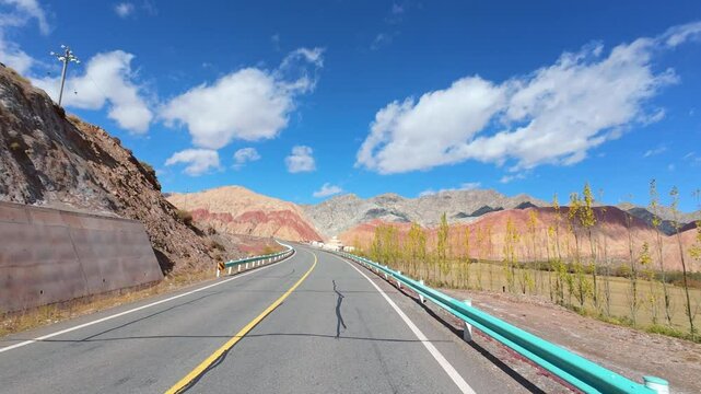 Driving on asphalt road passing through Gobi desert with colorful mountains on sunny autumn day in southern Xinjiang, China, POV from the car, 4k real time footage, travel concept.