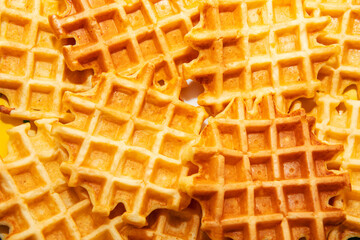 Waffles stacked together. Waffles have a classic grid pattern, with some areas appearing slightly toasted, giving them a varied texture. Crispy texture of the waffles, making them look delicious 