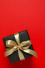 Beautiful gift box tied with golden bow on color background 