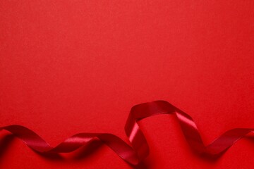 Beautiful red silk ribbon on color background, space for text © Sunlight