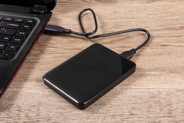 External backup hard disk drive connected to laptop on table.