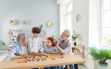 Grandparents playing board game with grandchildren at home, close-up. Children sitting at table...