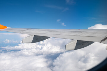 View from airplane window on wing and landscape with clouds on window during flight.