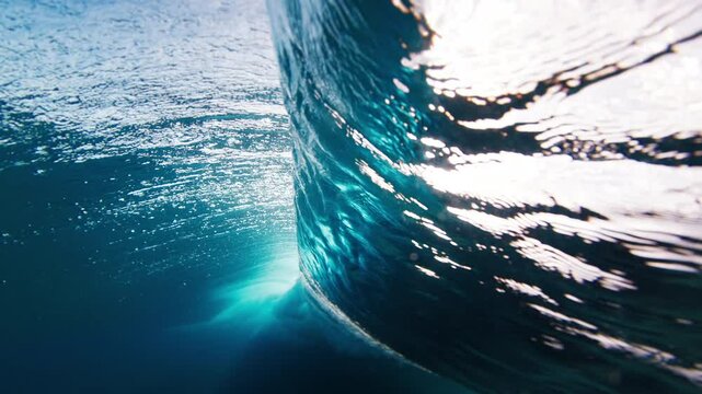 Ocean wave breaks over the reef bottom. Underwater view of a surfing spot in the Maldives
