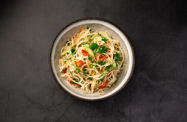 Salad with sprouts, celery and greens on a black background, top view