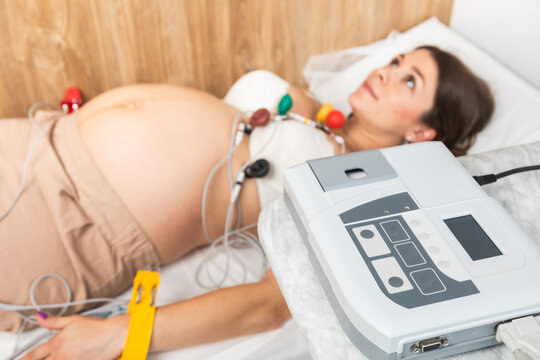 ECG machine and pregnant woman during cardiac monitoring procedure