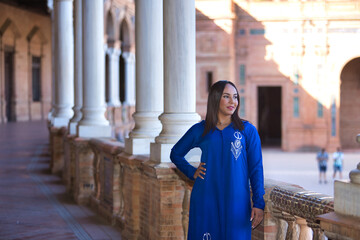 Moroccan woman, young, beautiful, brunette, with blue abaya, with her hand on her waist looking at...