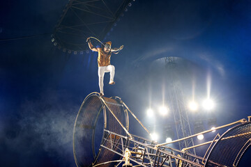 Brave male acrobats in the rotating wheel of death perform under the dome of the circus.