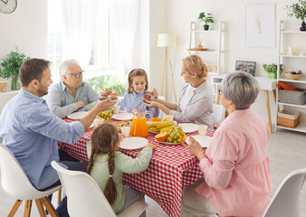 Portrait of a big joyful happy smiling family of young parents, senior grandparents and two children enjoying dinner together sitting at festive table during holiday celebration at home.