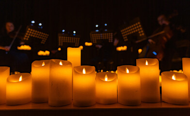 blurred symphonic orchestra on stage with lots of candles
