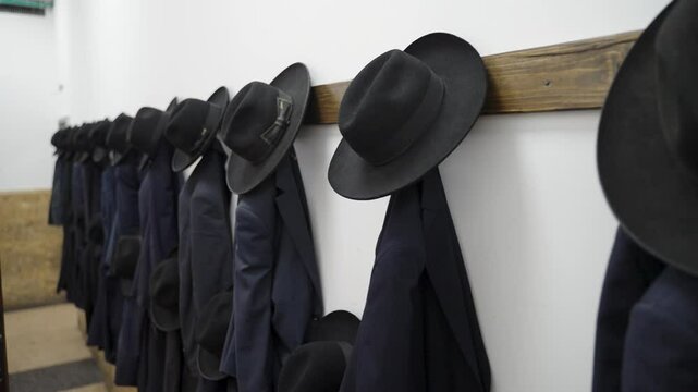 Forward Camera Movement Capturing Orthodox Jewish Coats and Hats Hung on Wooden Rack in Yeshiva, Israel