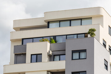 Modern apartment building with clean lines, rounded edges, and large windows. Features balconies with greenery, showcasing urban minimalist design. Bar, Montenegro