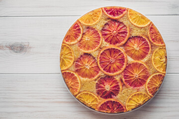 Delisious freshly baked homemade blood orange upside-down cake on white wooden background, top down view. Popular winter holiday dessert.
