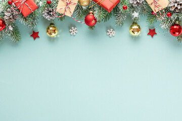 Christmas background with snowy fir tree branches, festive decorations, gift boxes and pine cones on pastel blue background. Flat lay. Happy New Year and winter holidays layout. Top view