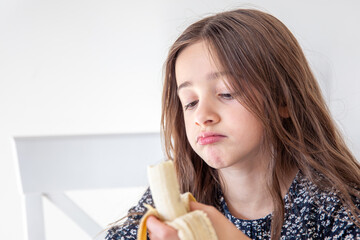 The girl is eating a banana. Concept of emotions.