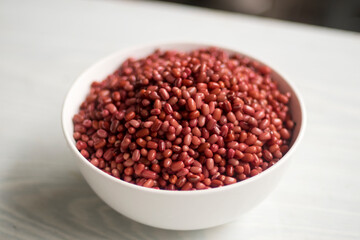 Azuki or Adzuki beans (Japanese red bean or red mung bean) after soaked in white bowl isolated on a table closed up. Selective focus blurred background.