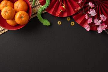 Colorful Chinese New Year arrangement featuring fresh oranges, red fans, cherry blossoms, and...