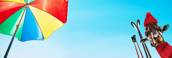 A quirky giraffe wearing a red hat, holding ski poles, under a colorful beach umbrella on a sunny day