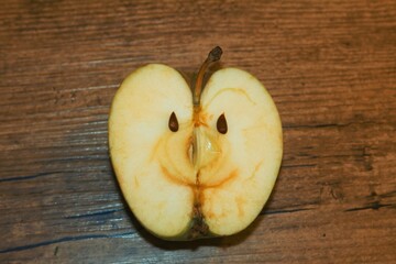 Happy apple fruit with face smiling on wooden background.