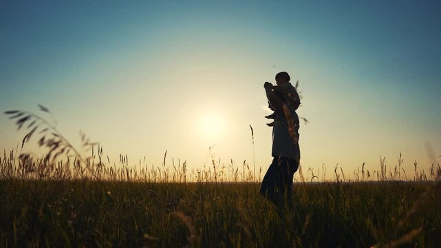 father and son in the park. father's day silhouette happy family child dream concept. father carries his son on his back. lifestyle dad walk with his son in nature in the park silhouette at sunset