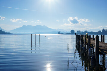 Wooden pier at Chiemsee, Bavaria, Germany in autumn. Sunny day, Bavarian Alps in the background