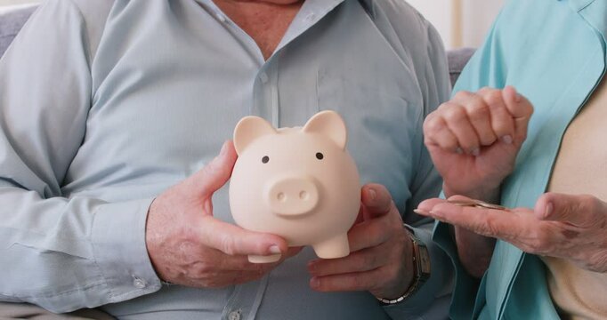 Senior retired pensioners counting pension in hand, putting small piggybank close up saving money for healthcare medical insurance, planning future investment, managing household budget, economy save