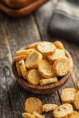 Sliced roasted bruschetta bread in bowl on wooden table.