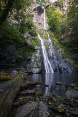 Obraz premium A waterfall falls in two stages over a quiet pool
