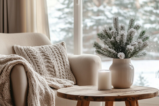 Cozy Living Room with Sofa, Knit Blanket, Wooden Side Table, Candle and Winter Wonderland View through Large Window