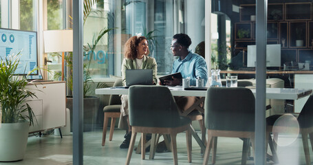 Business woman, man and tablet in office for discussion, deal and review with teamwork at startup. People, partnership and laptop for feedback, synergy and touchscreen in workplace at finance agency