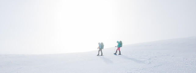 climbers climb the mountain in the snow. Winter mountaineering. two girls in snowshoes walk through the snow. mountaineering equipment. hiking in the mountains in winter.