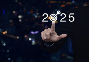 Businessman pressing 2025 letter with goal icon over blur colorful night light modern city tower...