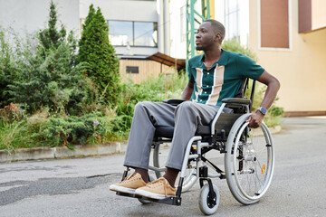 Obraz premium Full length portrait of active African American man with disability moving on concrete pavement in green city setting