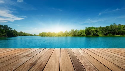 Fototapete Rund wooden floor against blue sky over lake with trees in the background © Dorothy