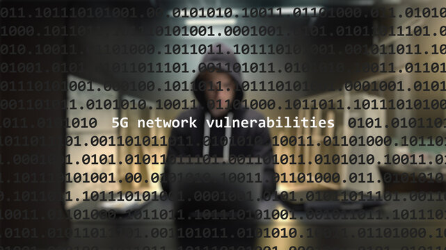 Cyber attack 5g network vulnerabilities text in foreground screen, anonymous hacker hidden with hoodie in the blurred background. Vulnerability text in binary system code on editor program.