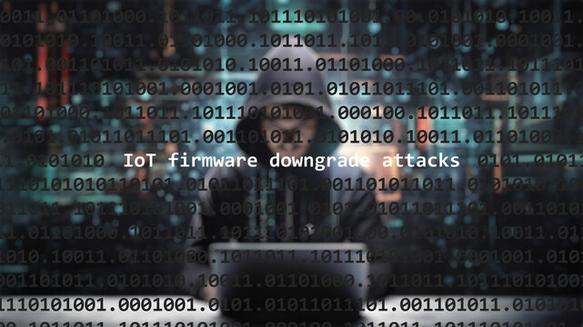 Cyber attack iot firmware downgrade attacks text in foreground screen, anonymous hacker hidden with hoodie in the blurred background. Vulnerability text in binary system code on editor program.