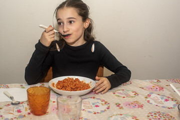 Bambina di dieci anni mentre mangia un piatto di orecchiette al sugo.