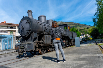 Obraz premium A woman stands in front of an old train engine