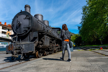 A woman stands in front of an old train engine