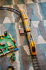 Fototapeta premium Lego brand electric toy train set with tracks on a carpeted floor in a room