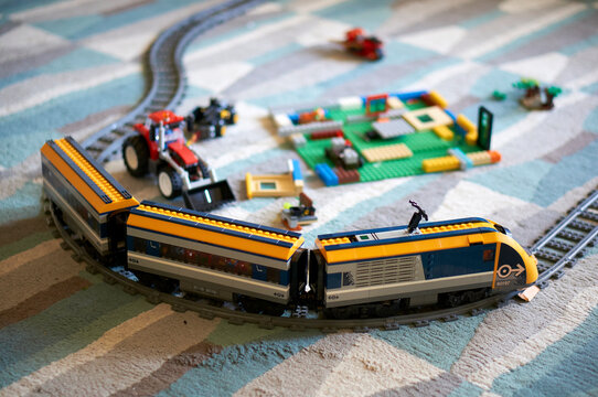 Close-up shot of a Lego brand toy electric train with tracks on a carpeted floor