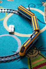 Naklejka premium Vertical shot of a Lego brand toy model train with track on a carpet floor.