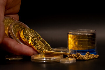 cluse-up hand counting gold coins on a back table with more gold. business, investments, finance and savings. Stock photo