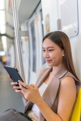 Asian Woman Using Tablet While Commuting To Work in a Public Train