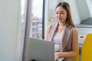 Obraz premium Asian Woman Using Laptop While Commuting in A Skytrain 