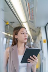 Asian Woman Using Digital Tablet While Commuting In A Skytrain 