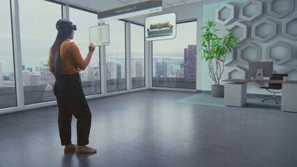Asian female designer wearing virtual reality headset uses AI augmented reality interior design app...