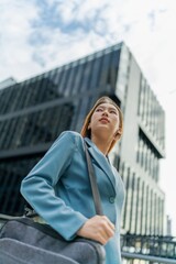 Fototapeta premium Portrait of a young and confident businesswoman standing in front a modern office building in the financial district