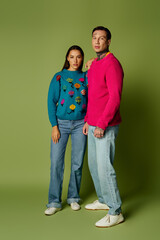 A stylish young duo showcases their unique fashion with bold sweaters and casual jeans.